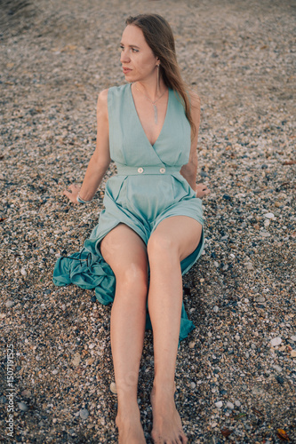 A woman in a flowing green dress poses on a pier by the sea at sunset, with a Turkey flag waving in the background.