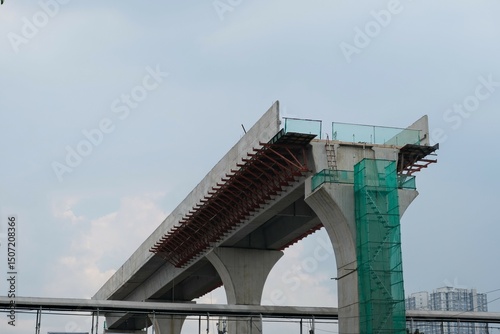 Concrete flyover under construction with exposed steel reinforcements and green safety netting
