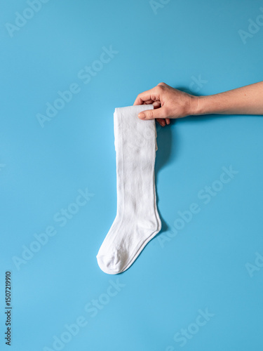 Hand is holding cotton white golf socks flat lay. Clothing production, sewing workshop