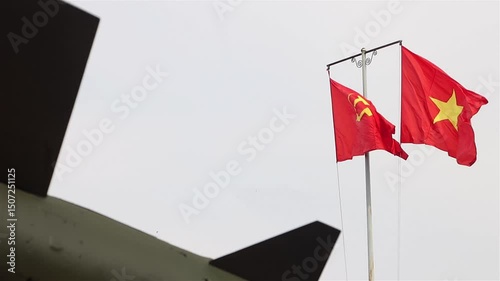 Red flags with communist symbols flutter on a flagpole above a air defence system missile The S-75 Dvina SAM 2, slow motion
