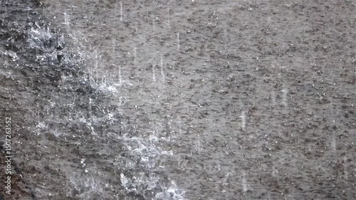 Heavy rainfall flood a stormwater drain on an urban road surface, slow motion