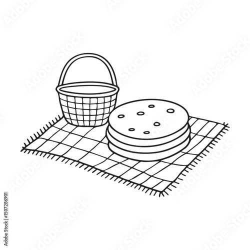 A tortilla stacked near a basket on a picnic mat