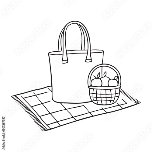 A tote bag beside a fruit basket on a picnic cloth