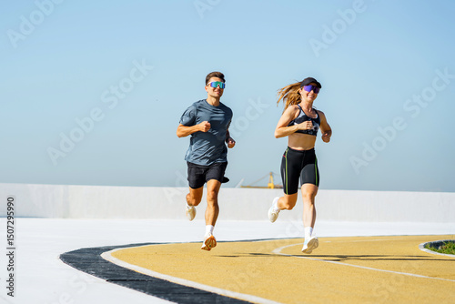 Papier peint Energetic couple enjoys morning run on bright sunny day along outdoor track with