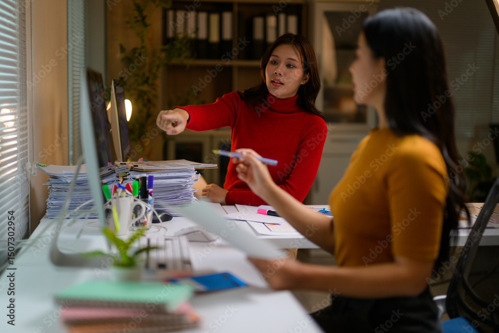 Fototapeta premium Asian businesswomen working together using computer and documents in office at night