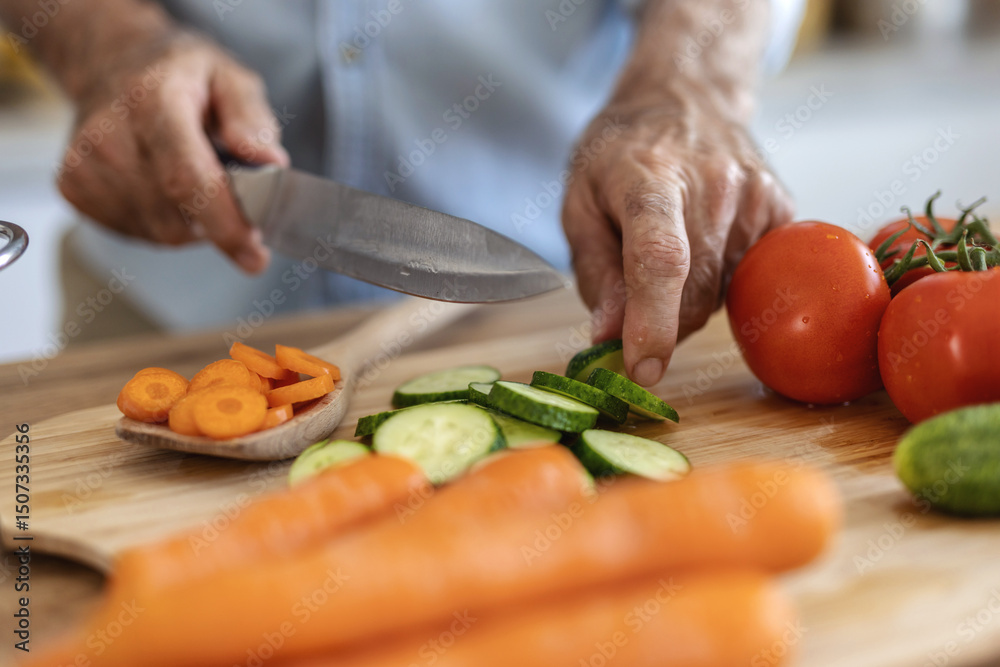 Hands, food and nutrition with a man cooking in the kitchen while cutting vegetables on a wooden chopping board. Salad, health or diet with a chef preparing a meal while standing alone in his home. Hands, food and nutrition with a man cooking in the kitchen while cutting vegetables on a wooden chopping board. Salad, health or diet with a chef preparing a meal while standing alone in his home.