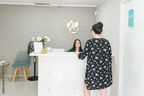 Woman being assisted by receptionist at clinic front desk