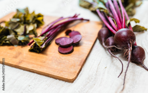 Fresh beetroot on a rustic table cloth and beet cuts on a cutting board. Process of preparing beetroot for cooking. Local food concept.
