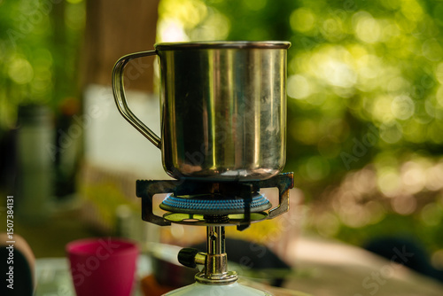 A metal mug is heated on a burner on a hike
