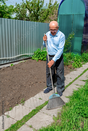 An elderly gentleman is sweeping the paving slabs in the garden — a quintessential scene of rural life.