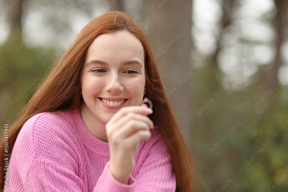 Red-haired woman smiles happily and contemplates her engagement ring Red-haired woman smiles happily and contemplates her engagement ring