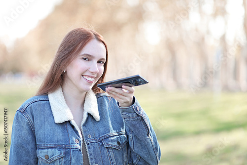 Long-haired woman walks through a park dictating on her mobile phone
