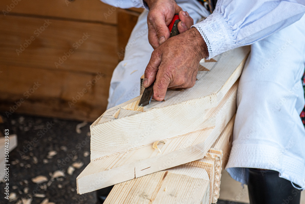 Woodcarvers hands carving decorative patterns on wood with traditional tools