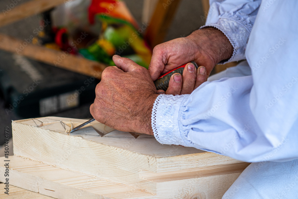 Woodcarvers hands carving decorative patterns on wood with traditional tools