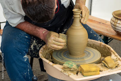 Obraz na płótnie Potters hands shaping a clay jug on a pottery wheel at a traditional craft festival w salonie