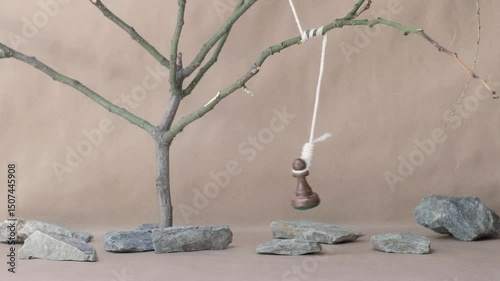 chess piece black pawn hanging on noose among stones on beige background