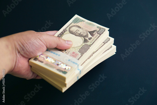 黒いテーブルに置かれた一万円札の札束 photo