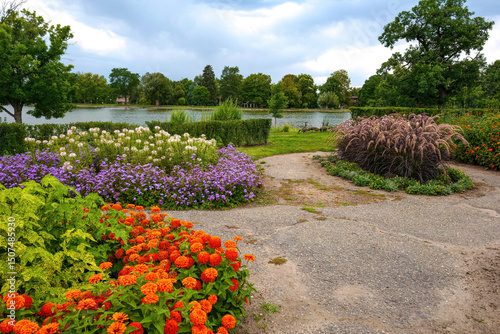 Mount Vernon Gardens by the lake at Washington Park in Denver, Colorado with colorful flowerbeds filled with Zinnias, Floss Flowers, Cleome and Purple Fountain Grass.