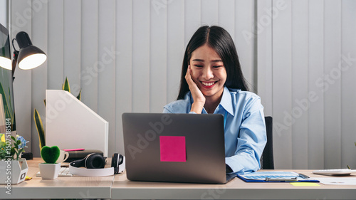 Secretary woman sitting with hands on chin and looking on laptop to watching movie for relaxation while feeling happy