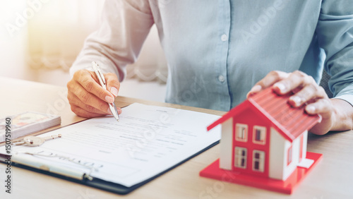 Real estate broker agent holding house model and sending to the customer after signing rental lease contract of the sale purchase agreement