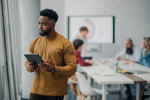 Photography Pensive businessman holding tablet, observing meeting in modern office