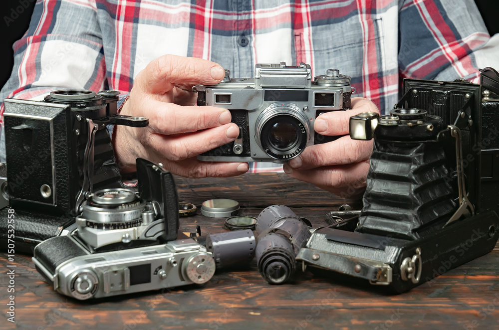 Fototapeta premium An elderly collector studies old cameras. Close-up.