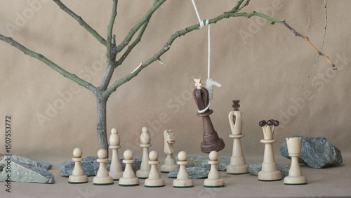 chess piece black king hanging on noose among white chess pieces