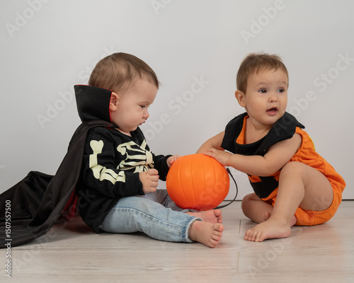 Cute kids celebrate halloween on white background. Two little boys in dracula costume and pumpkin.  photo