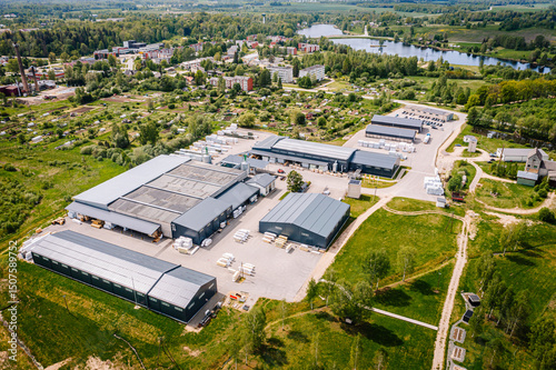 Konstfotografi Aerial view of a rural industrial zone near a small town and lake, with warehouse buildings, roads, fields, and surrounding residential areas