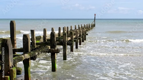 Wooden breakers in the sea on Overstrand beach on the North Norfolk Coast. Captured on a bright and sunny day. Pull back shot
