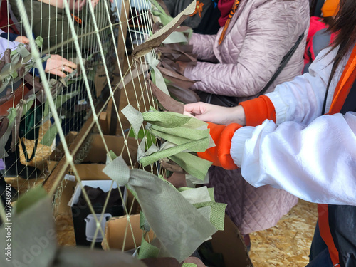 Women's hands knit a camouflage net to protect equipment and people
