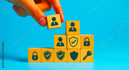 Hand placing a wooden block with a person icon on top of a pyramid of security themed blocks
