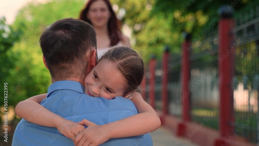 Fototapeta premium Loving father tenderly embraces his daughter in summer park day outdoor. Happy family closeup, dad hugs his child girl on walk in city park with green trees. Happy childhood, happy family kid girl mom