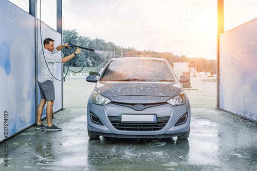 Man cleaning car. Spray hose foam soap. Car wash water shine exterior.