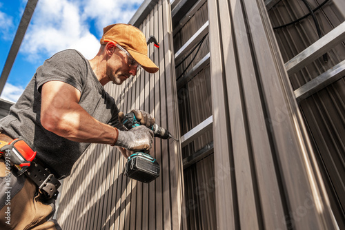 Construction Worker Installing Lamella Composite Panels on a Building During a Sunny Day in a Suburban Area