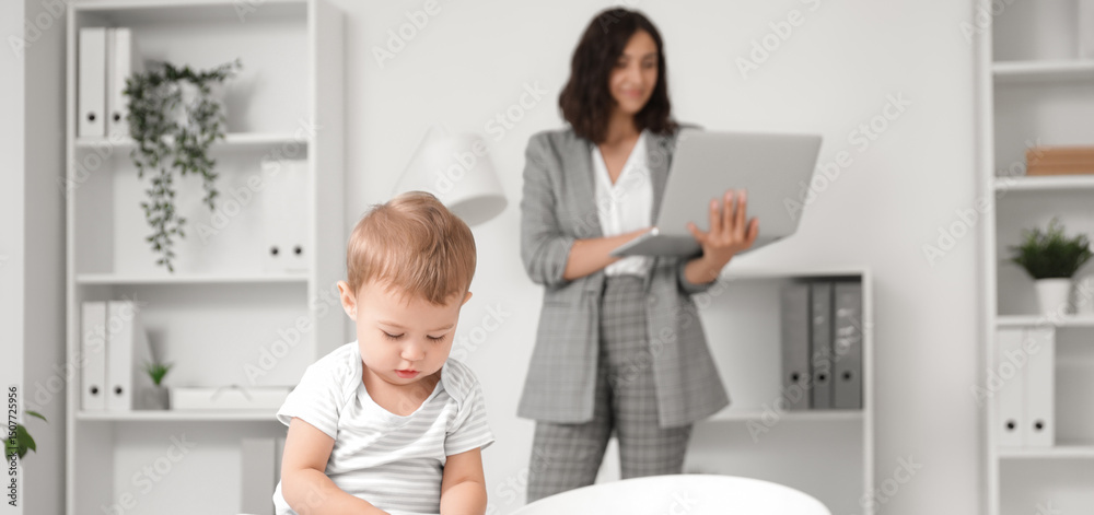 Fototapeta premium Cute little baby playing with cubes on desk while mother working in office