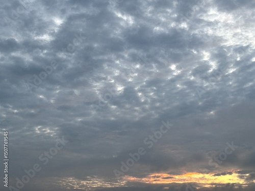 a sky filled with altocumulus clouds with a wavy pattern, creating an interesting texture in the sky. Sunset or faja, golden and grayish blue tones are suitable for backgrounds, atmospheric designs