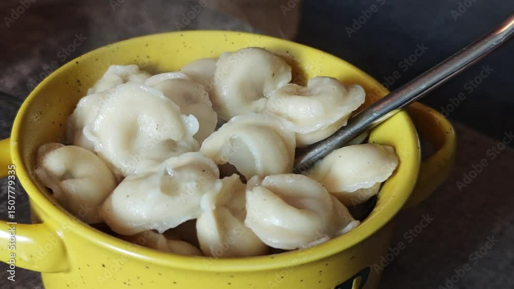 Freshly cooked pelmeni dumplings releasing steam, served in a yellow pot and ready to be enjoyed Freshly cooked pelmeni dumplings releasing steam, served in a yellow pot and ready to be enjoyed