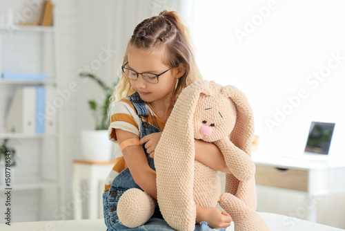 Little girl with medical patch and toy after vaccination in clinic