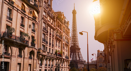 Fototapeta Naklejka Na Ścianę i Meble -  Sun shining over typical Parisian buildings with Eiffel Tower in the background at sunset
