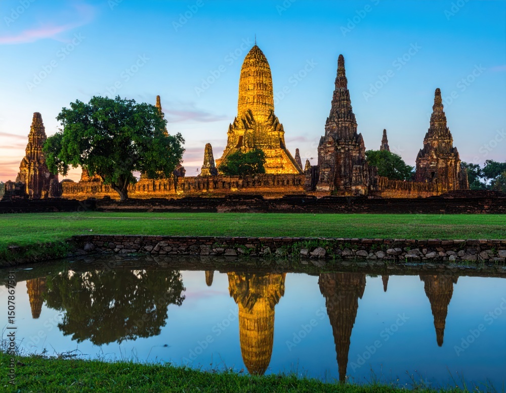 Obraz premium Ancient temple complex at dawn, reflected in still water. Golden pagodas, serene landscape