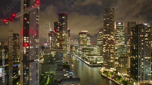 Quickly running clouds above illuminated futuristic Canary Wharf district