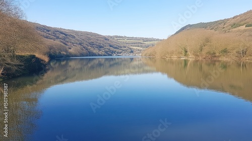 Serene lake reflecting hills under a clear sky