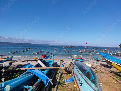 Colorful fishing boats rest under a bright blue sky on a peaceful tropical beach.