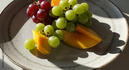 Sunlit Plate of Fresh Mango Red Green Grapes Healthy Fruit Snack