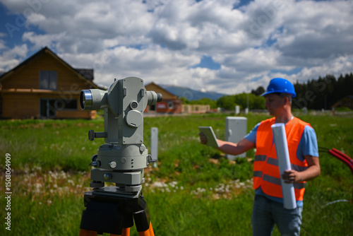 Foto Surveyor working with theodolite and tablet during land surveying for new house