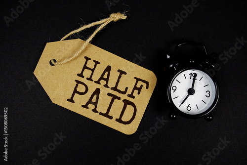 Half Paid text on price tag with alarm clock on black background
