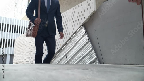 Smart business man walking up the stairs with confident near building. Skilled project manager walking on stairs seeking for job, going for new job near at modern skyscraper. Copy space. Exultant.