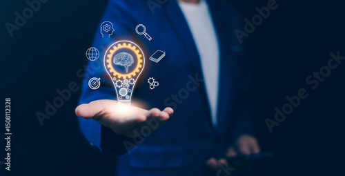 Obraz na płótnie Concept of innovation, artificial intelligence, strategic business solutions. A hand hold a glowing light bulb with a brain and digital icons, new ideas, technology advance, and smart thinking future w salonie