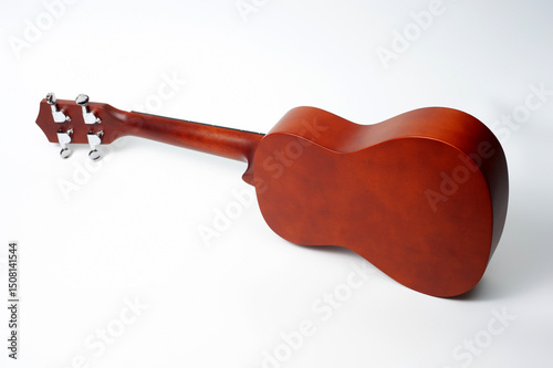 Ukulele made of natural wood of dark color photographed on a white background.